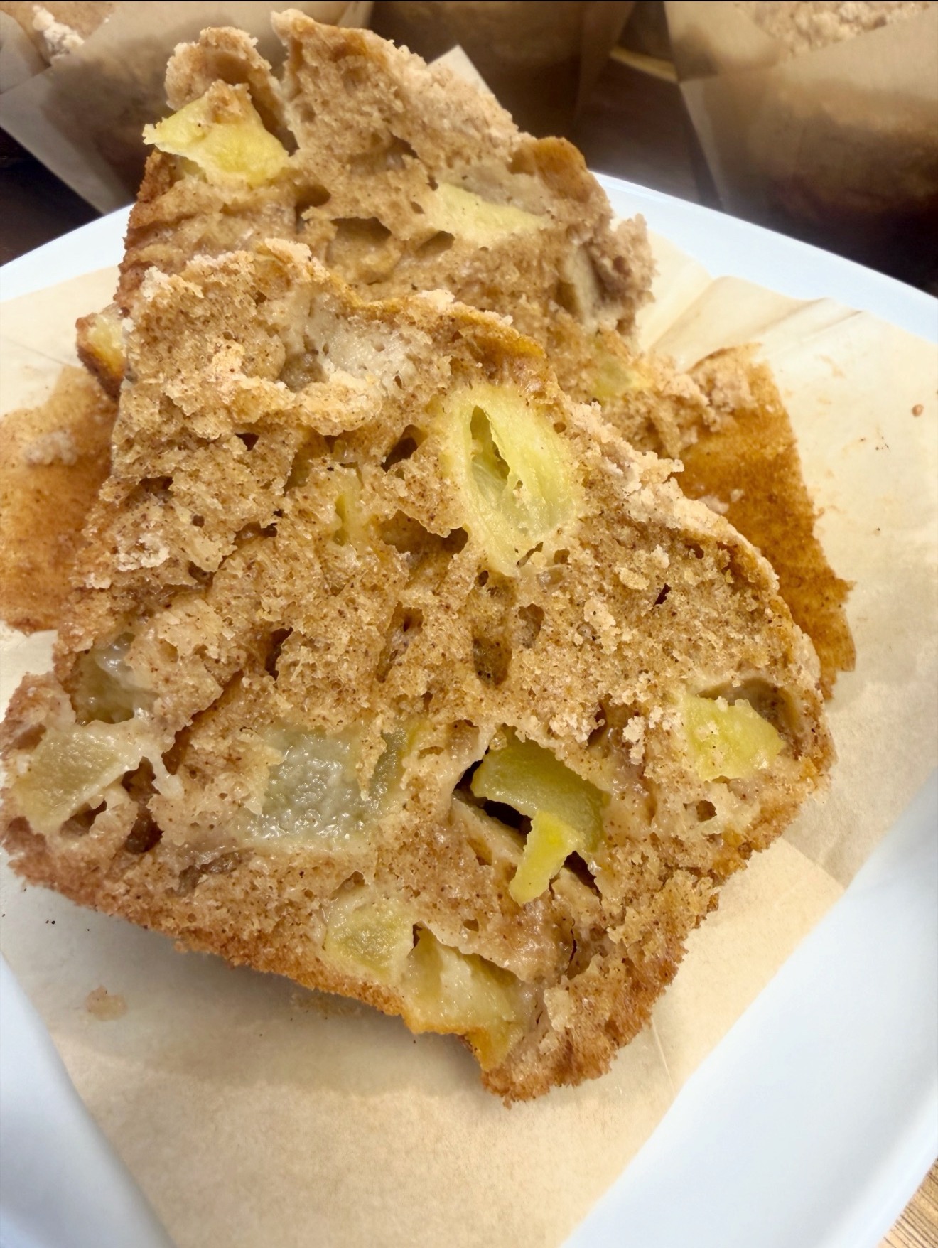 An apple crumble muffin broken open to show tender crumb and apple pieces