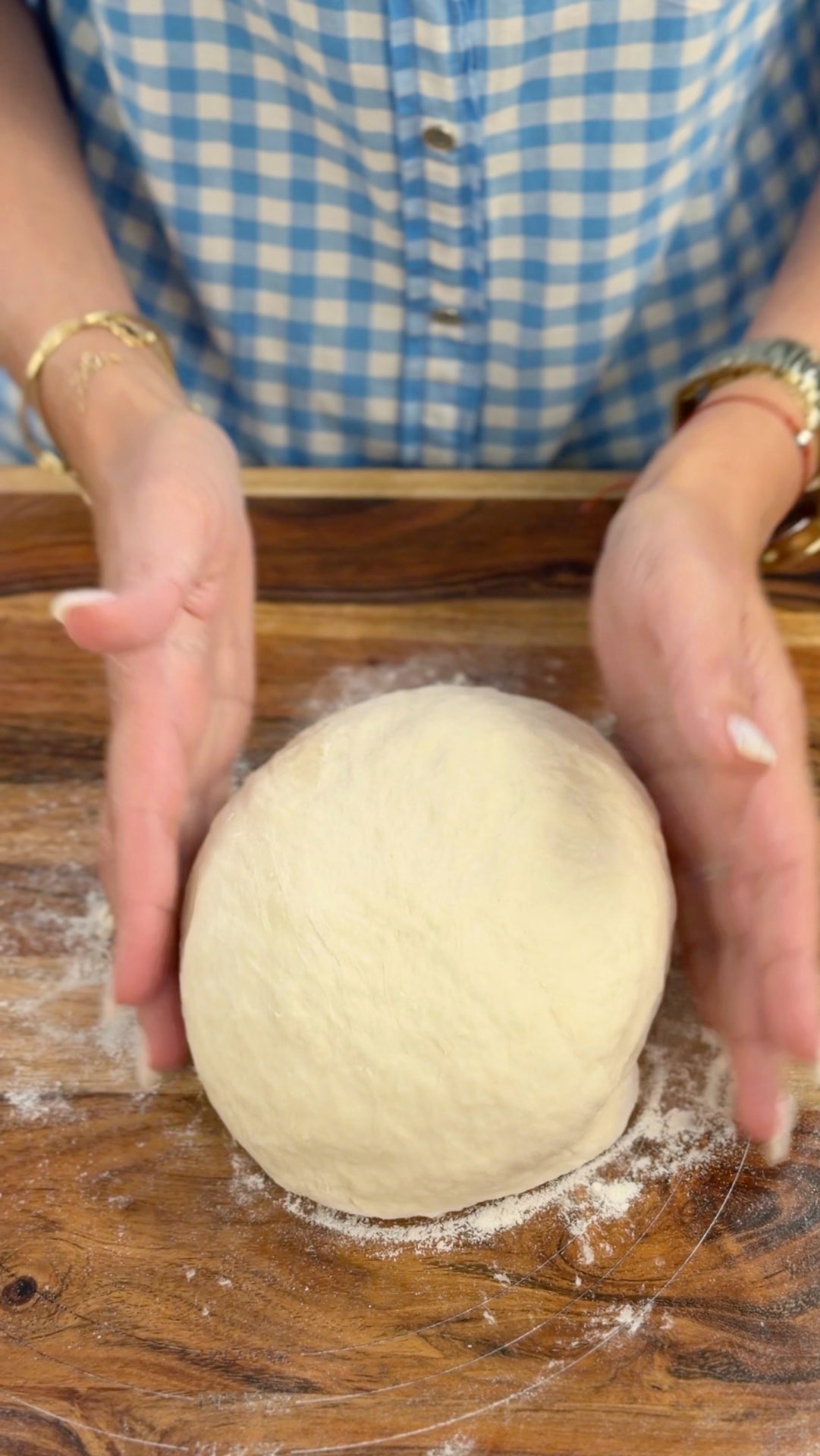 Shaping the soft kneaded dough into a smooth ball on a floured board
