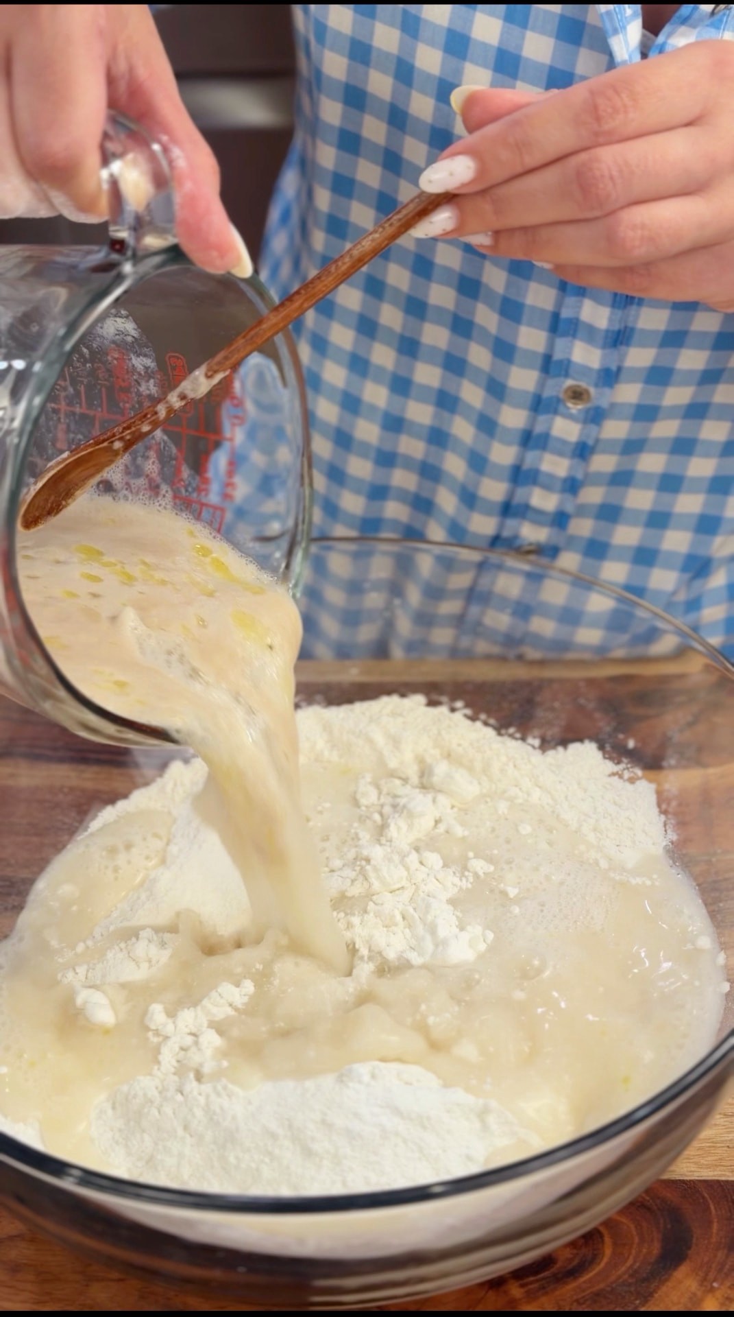 Pouring the activated yeast, water, and oil mixture into a bowl of flour