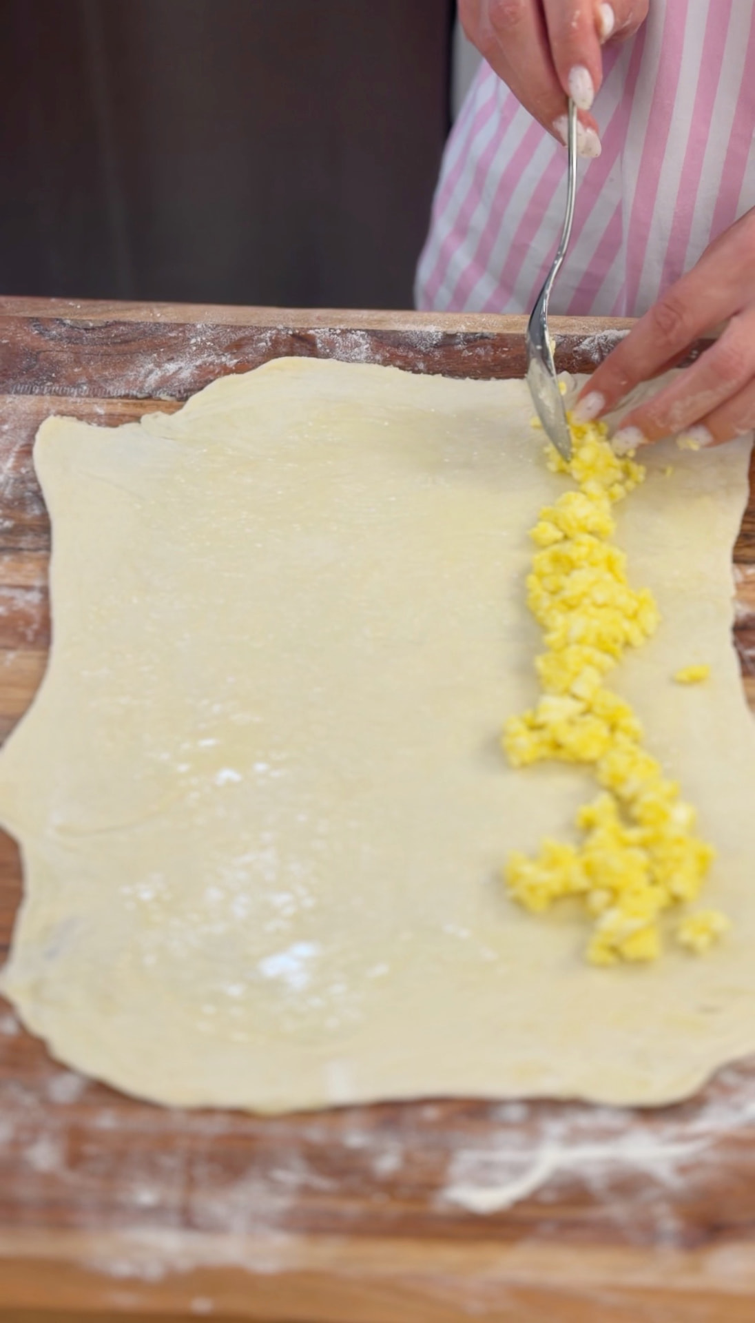 Spooning the feta-and-egg filling along one side of the buttered dough