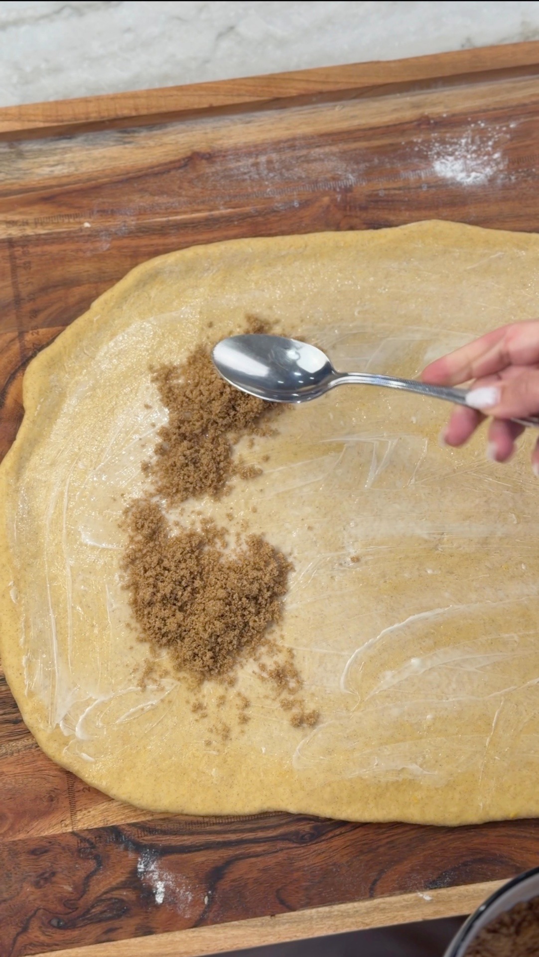 Spreading cinnamon sugar over the buttered dough