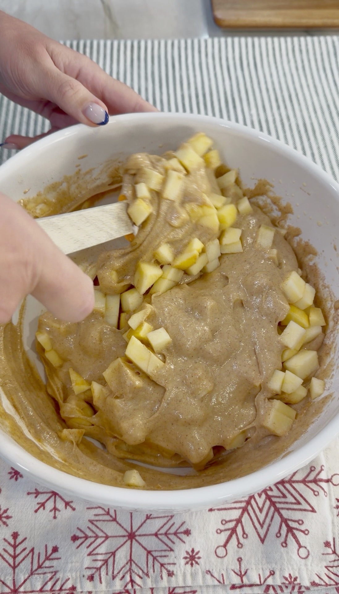 Gently folding apple pieces into the muffin batter