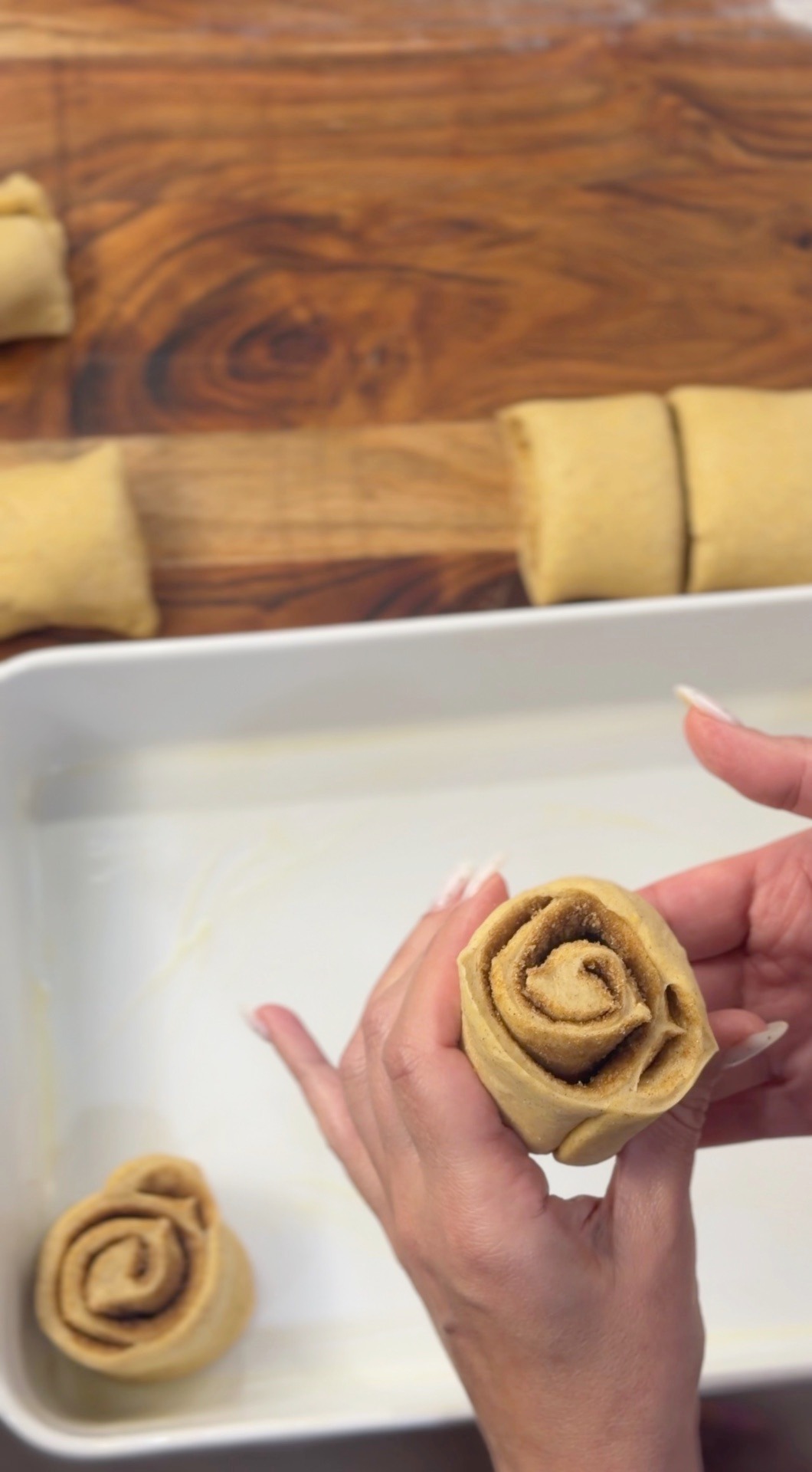 Placing a sliced cinnamon roll into the baking dish