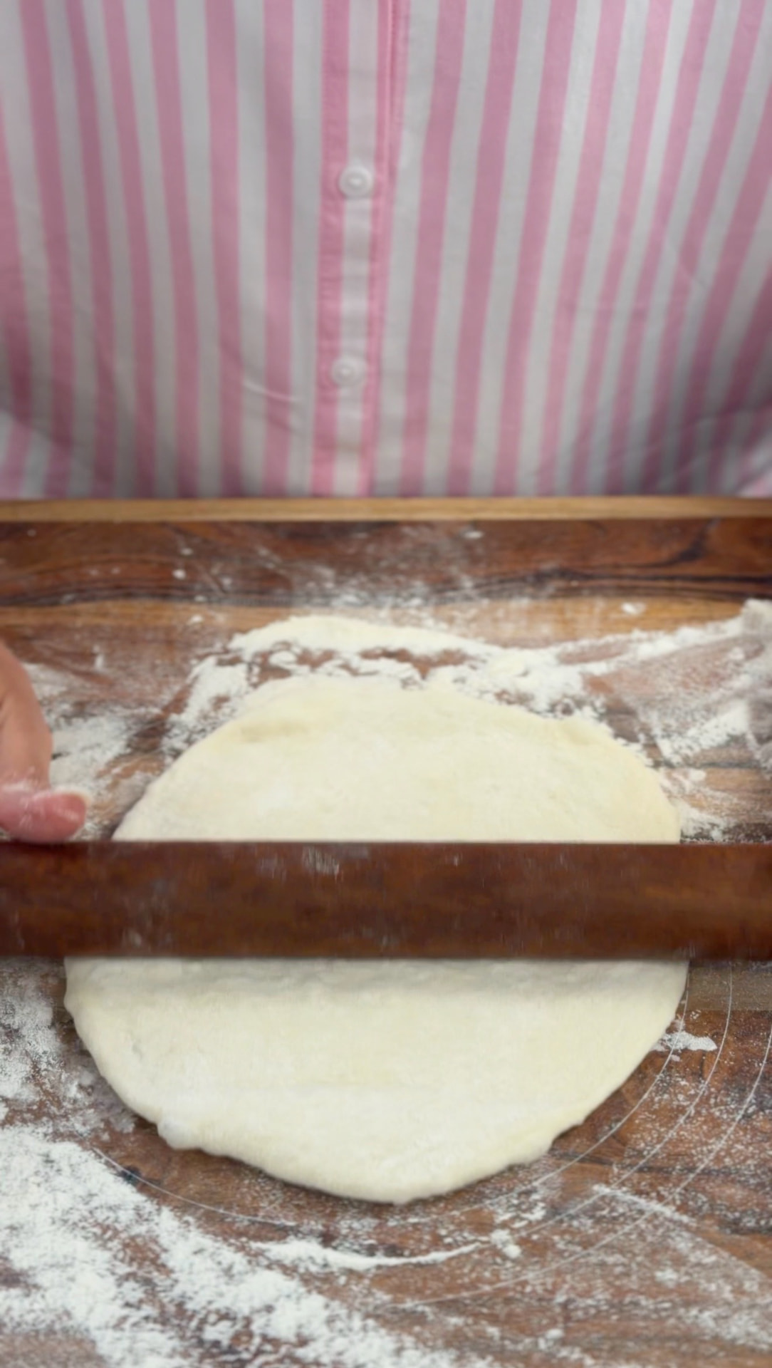 Rolling a dough piece into a thin sheet with a wooden rolling pin