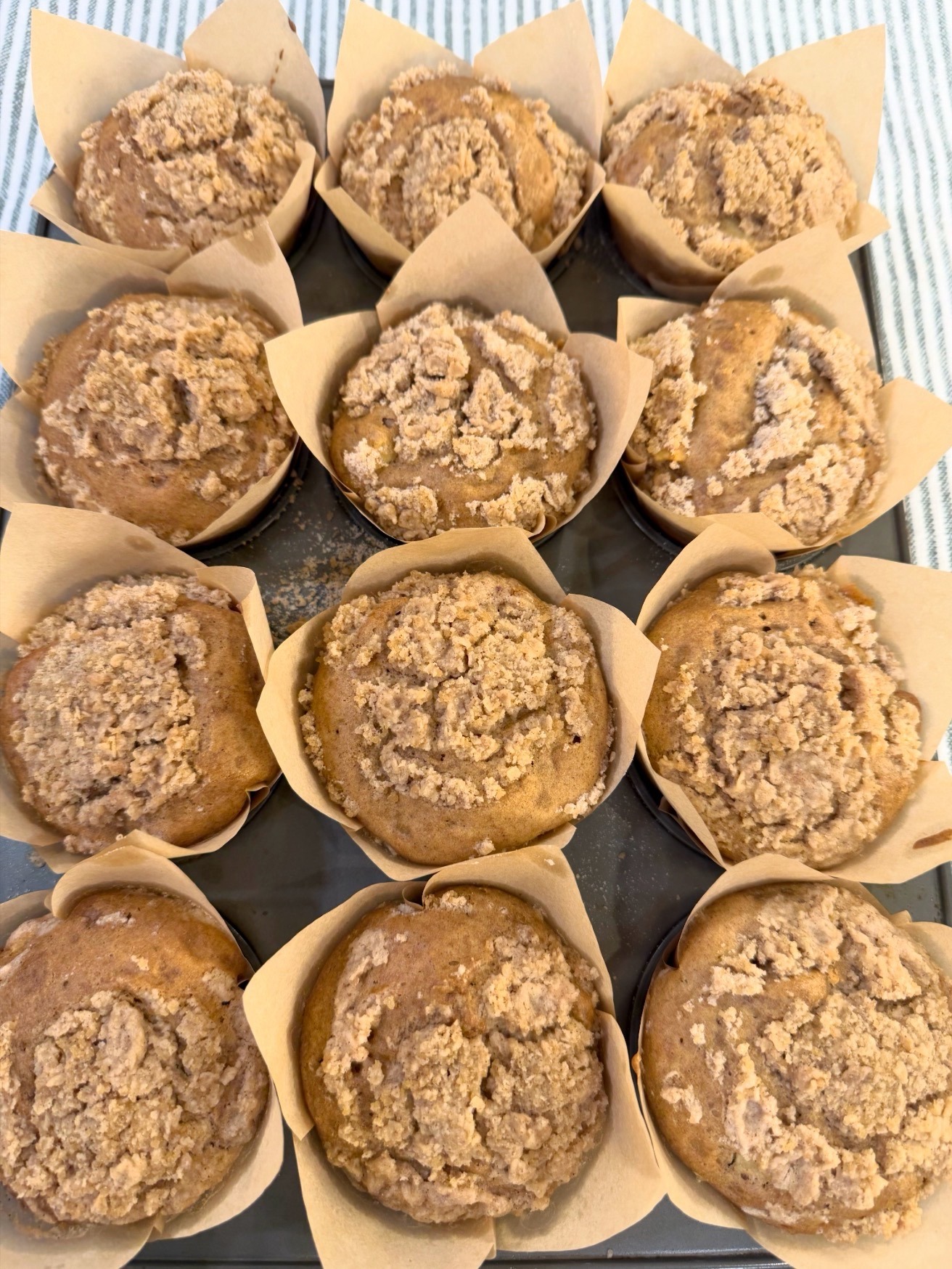A pan of twelve golden apple crumble muffins after baking