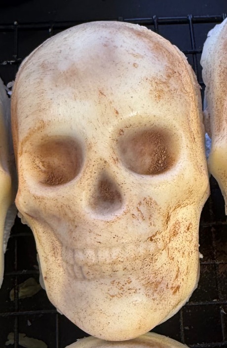 Close-up of a white candy-coated skull treat with cocoa powder highlighting the eyes, nose and teeth