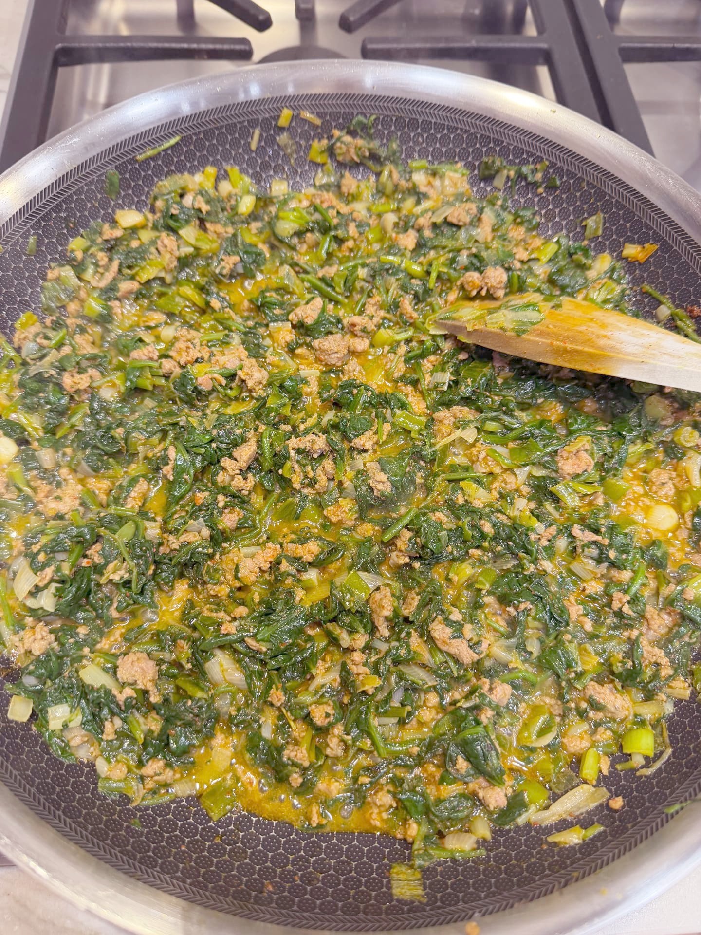 The spinach and ground meat filling cooking down in the skillet