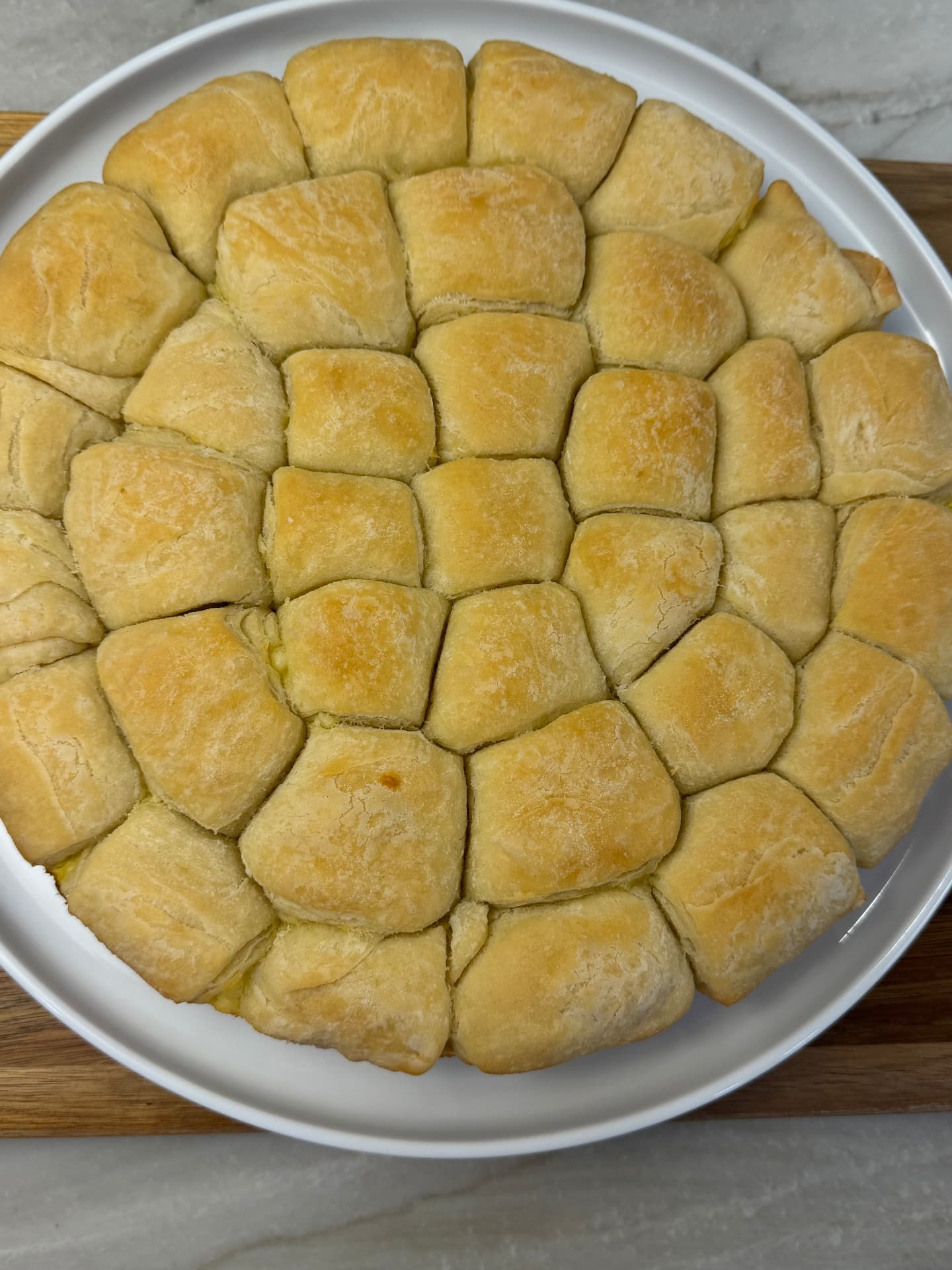Baked tutmanik rolls served in a white oval dish on a wooden board