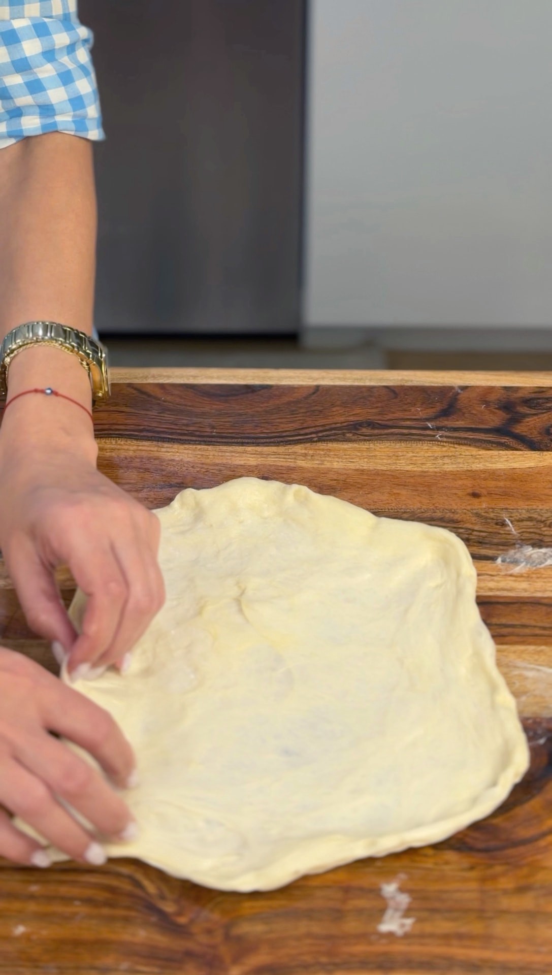 Stretching a risen dough disk by hand into a large, thin sheet