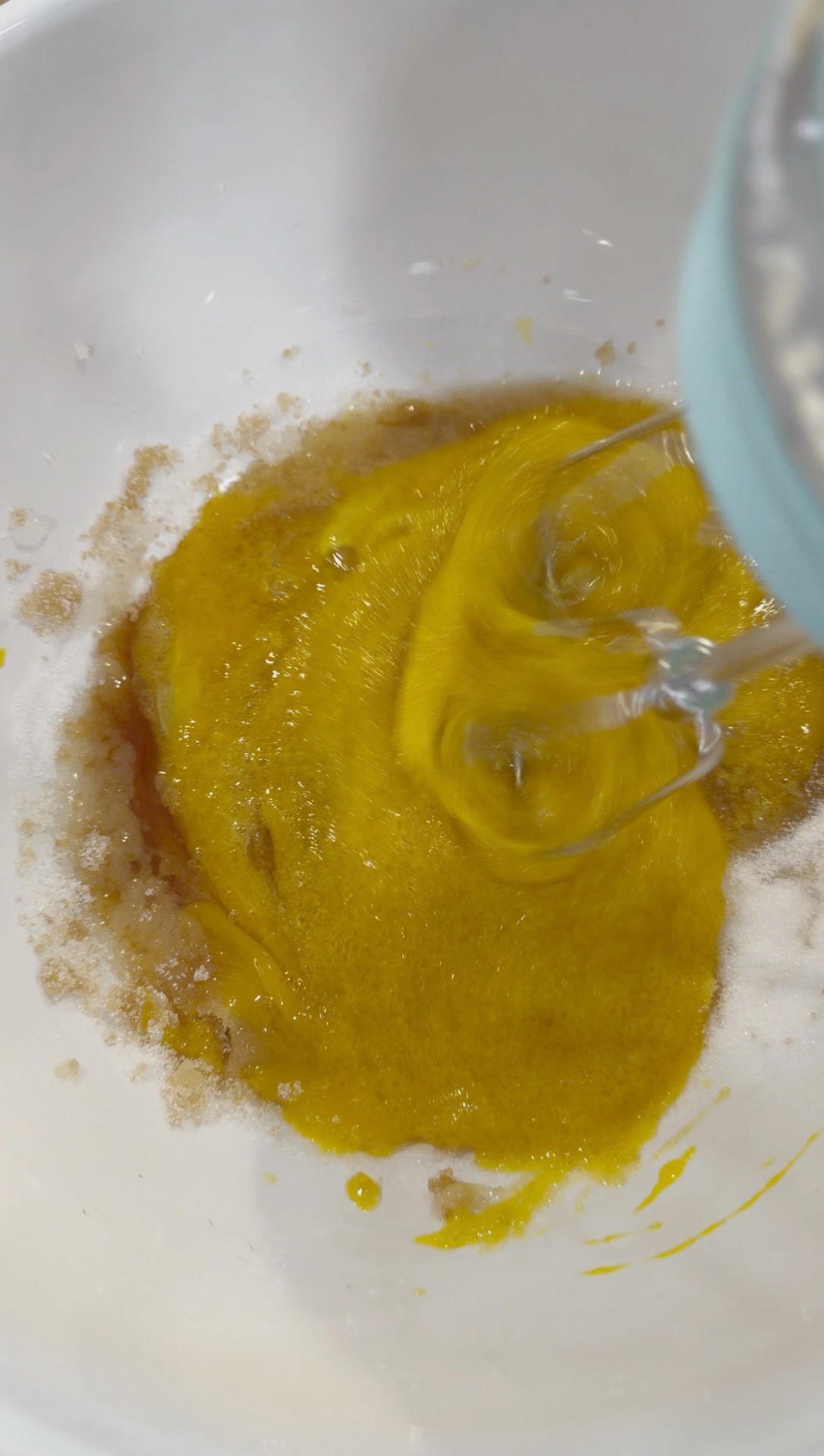 Mixing the wet muffin ingredients with an electric mixer