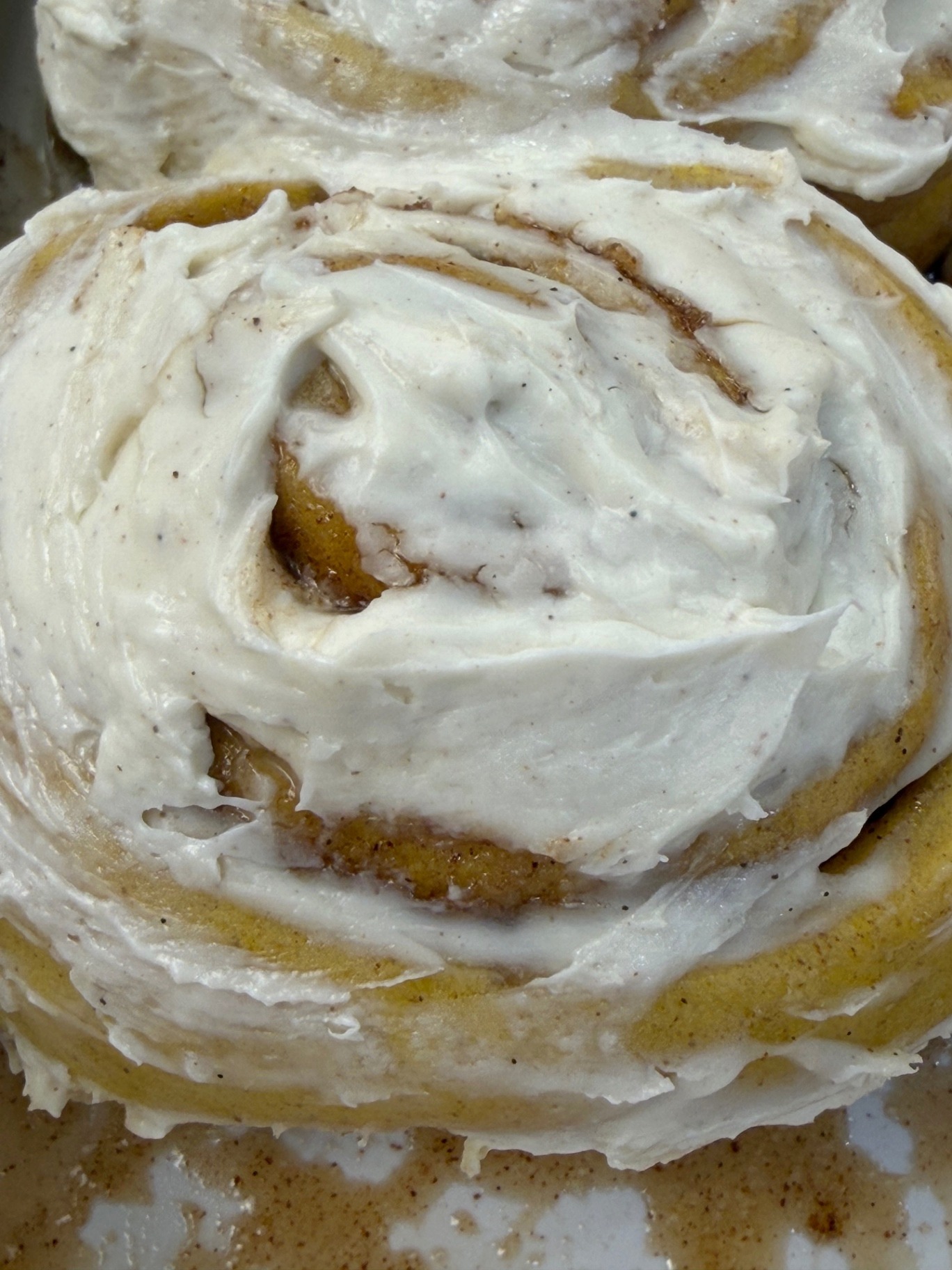 Close-up of a pumpkin cinnamon roll with cream cheese frosting