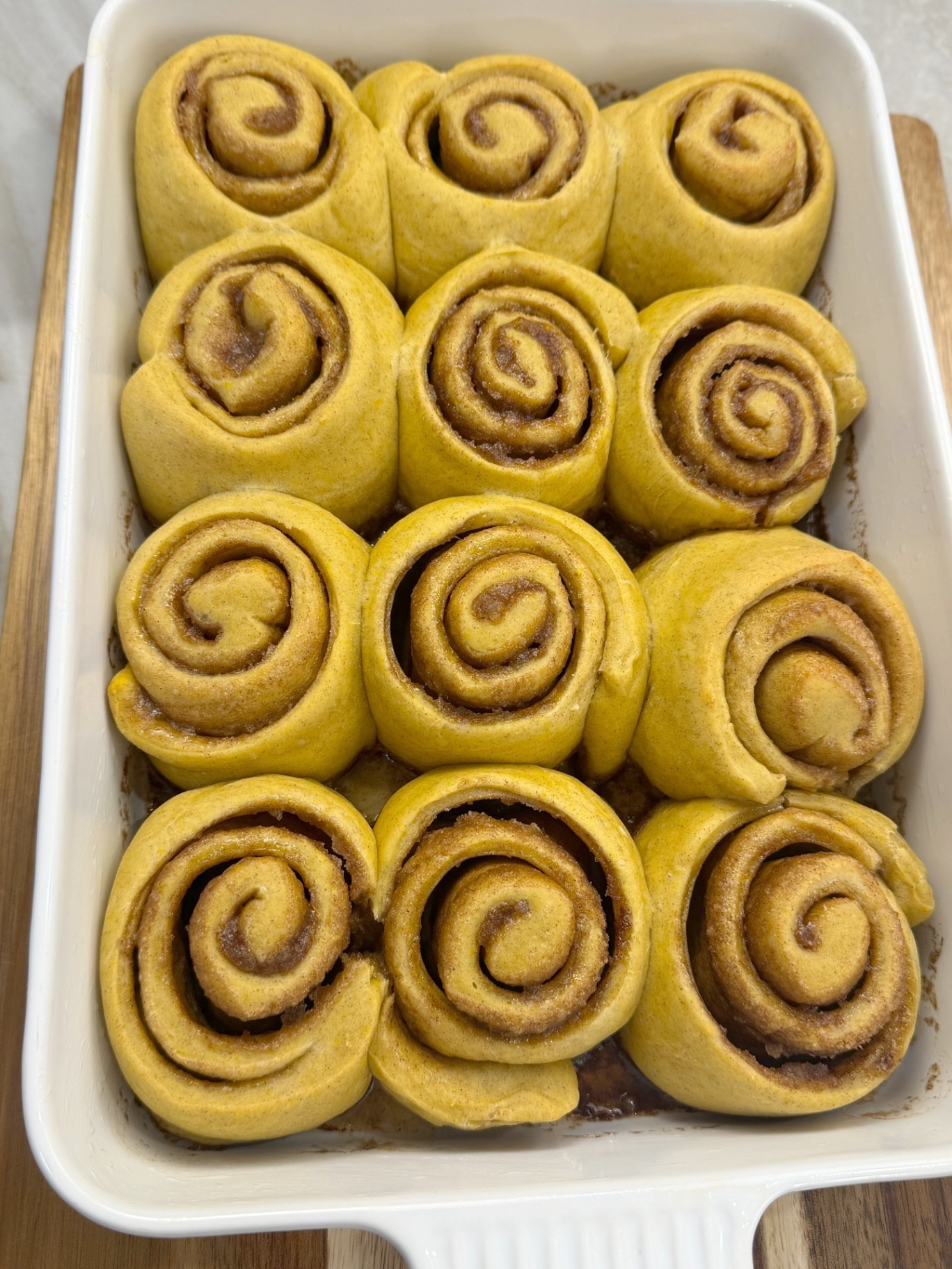 Unbaked pumpkin cinnamon rolls arranged in the dish