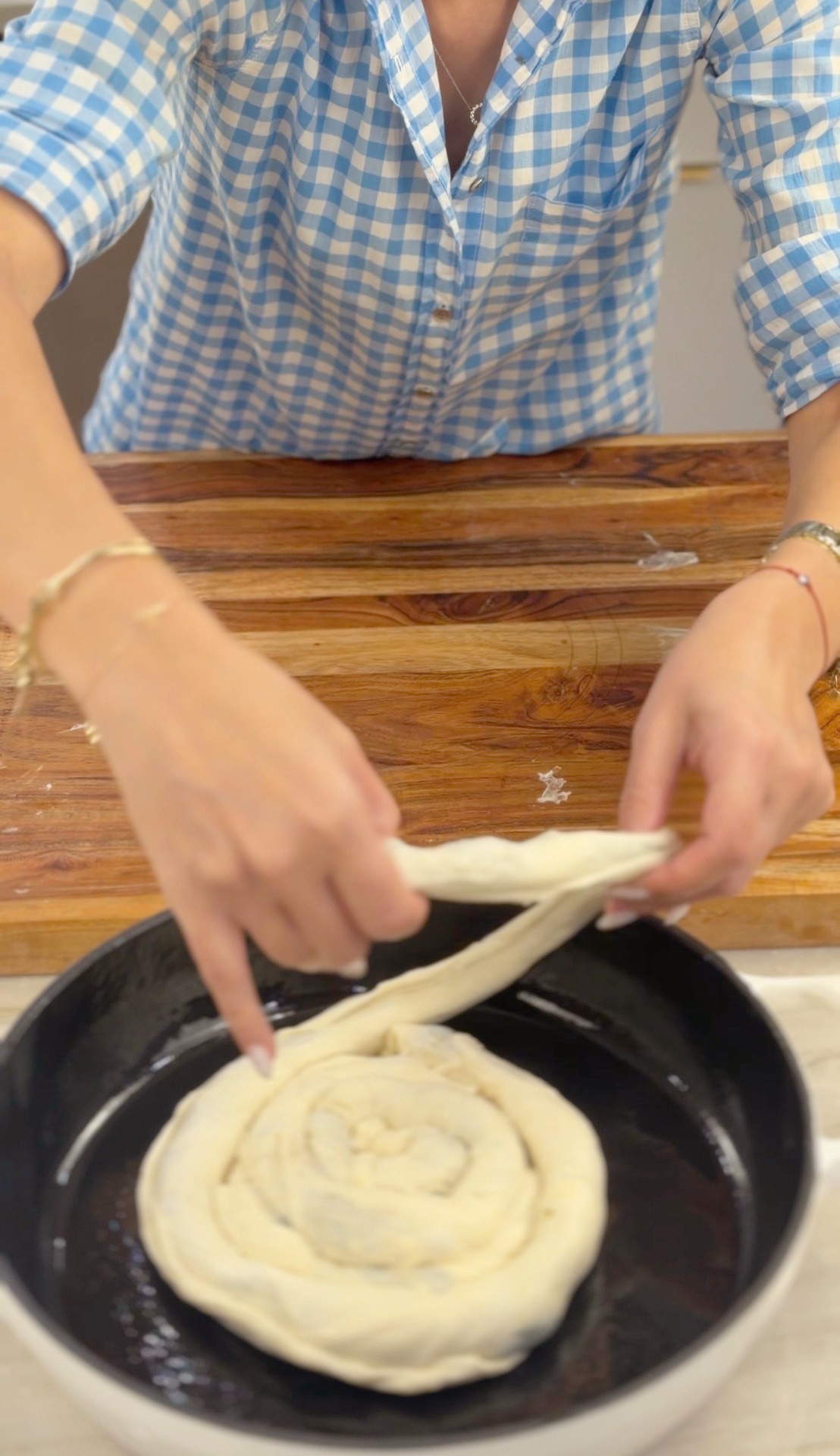Coiling the filled dough rope into a spiral inside the baking pan
