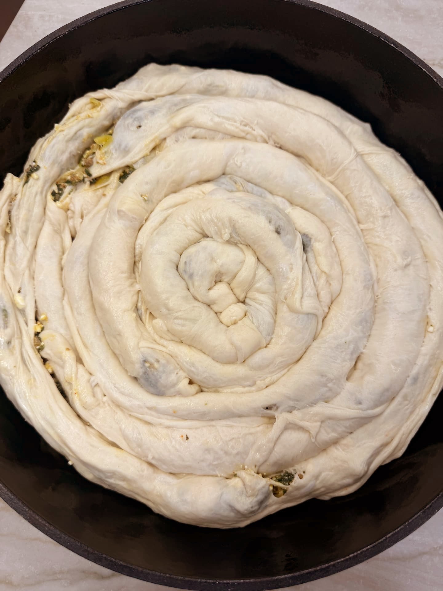 The assembled raw banitsa spiral in the pan, ready for the oven