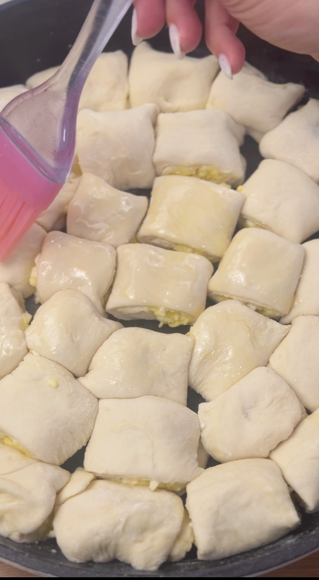 Brushing the tops of the arranged pieces with melted butter