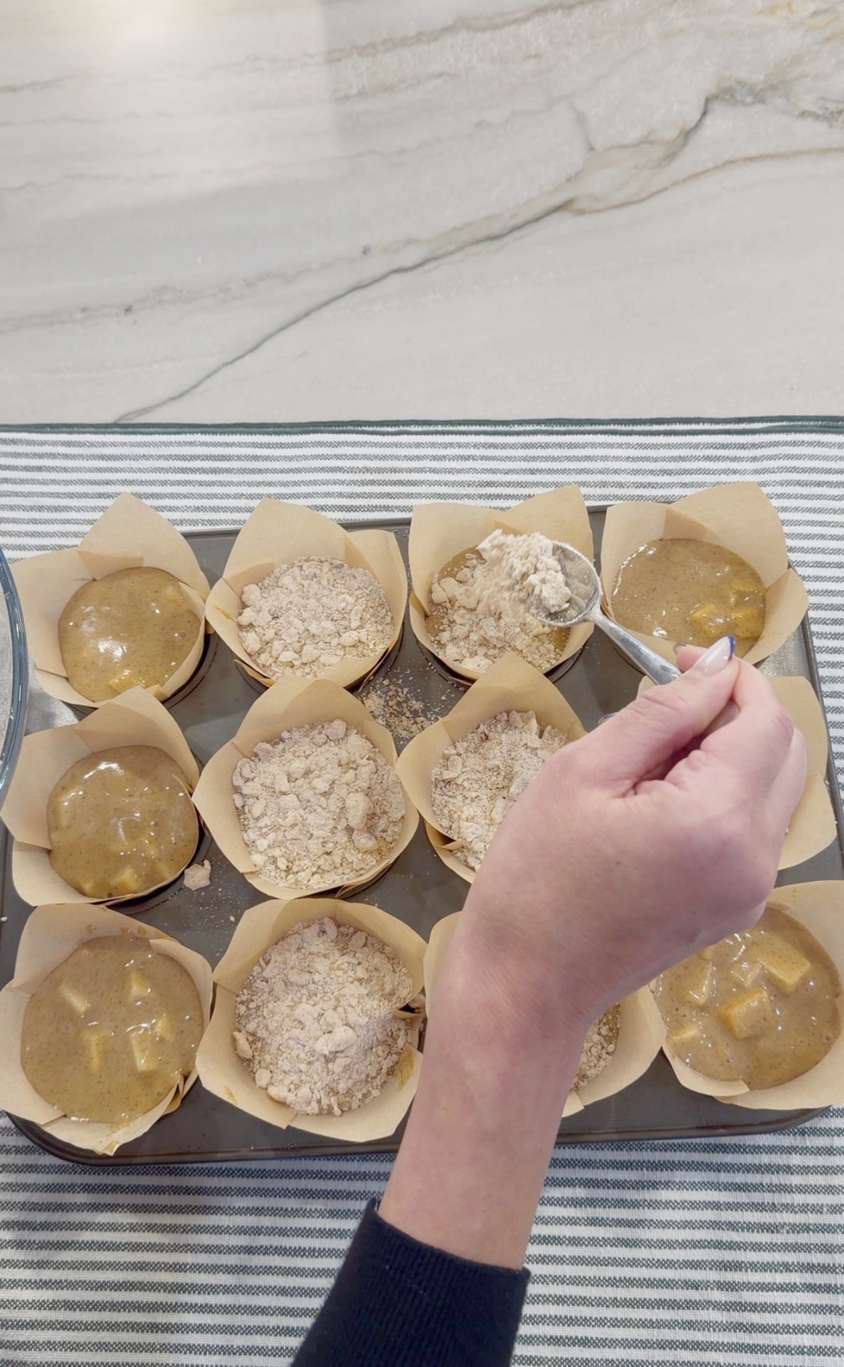 Spooning crumble topping over the apple muffin batter